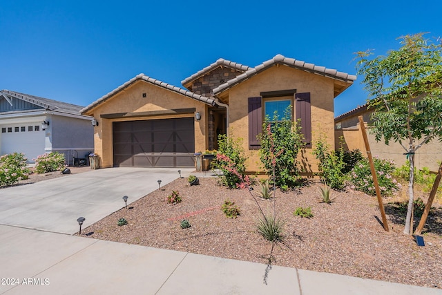 view of front of house featuring a tile roof, driveway, an attached garage, and stucco siding