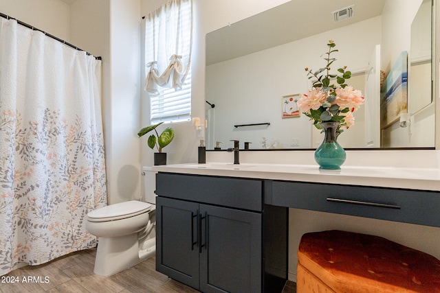 bathroom with visible vents, toilet, a shower with curtain, wood finished floors, and vanity