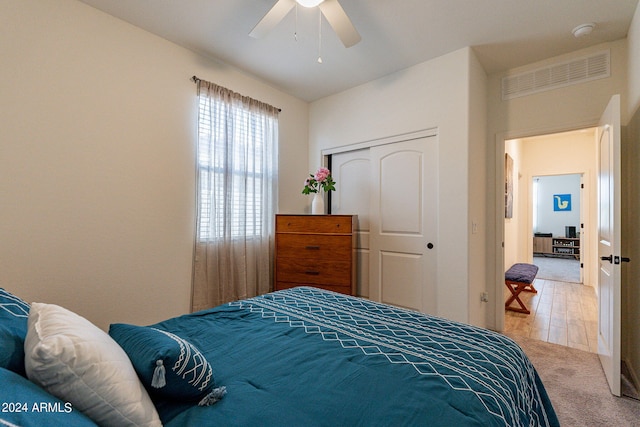 carpeted bedroom featuring a ceiling fan, visible vents, and a closet