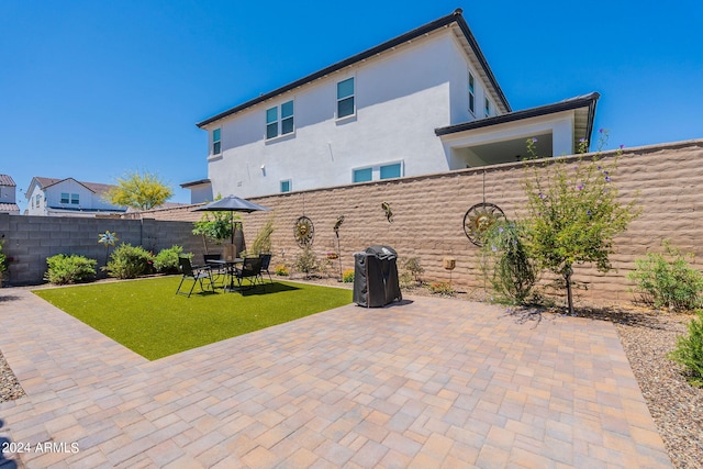 back of house with a patio, a yard, a fenced backyard, and stucco siding