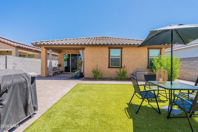 rear view of property featuring a patio area, fence, a lawn, and stucco siding