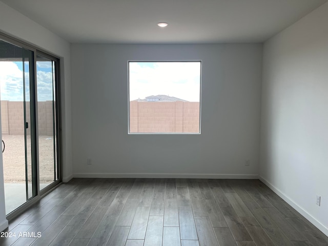 empty room featuring plenty of natural light and dark hardwood / wood-style floors