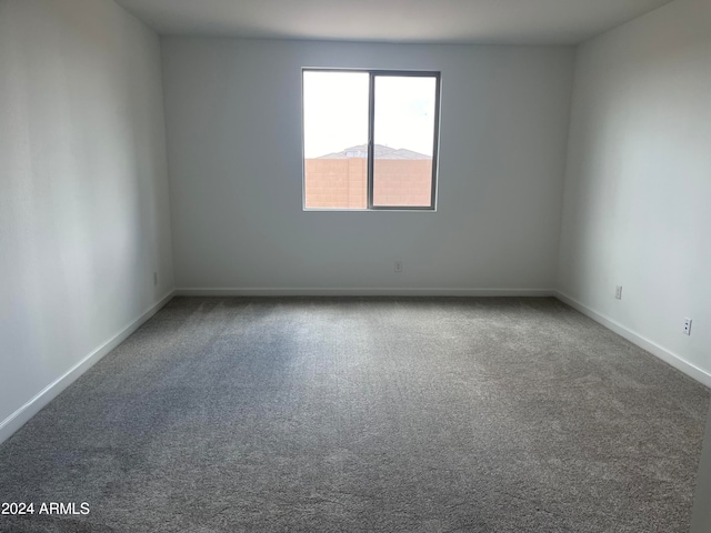 unfurnished room with a mountain view and carpet floors