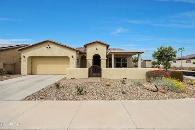 mediterranean / spanish home featuring a tiled roof, stucco siding, a gate, an attached garage, and concrete driveway