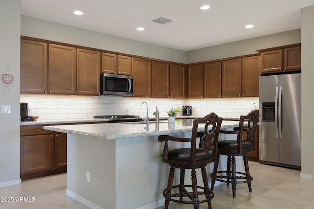 kitchen featuring tasteful backsplash, a kitchen breakfast bar, visible vents, appliances with stainless steel finishes, and a sink