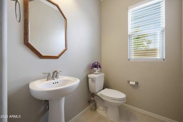 half bath with tile patterned flooring, baseboards, and toilet