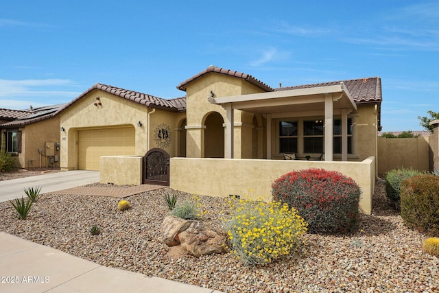 mediterranean / spanish-style house with a garage, driveway, stucco siding, and a fenced front yard