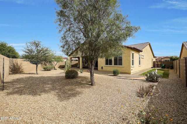 exterior space featuring a fenced backyard, a tiled roof, and stucco siding