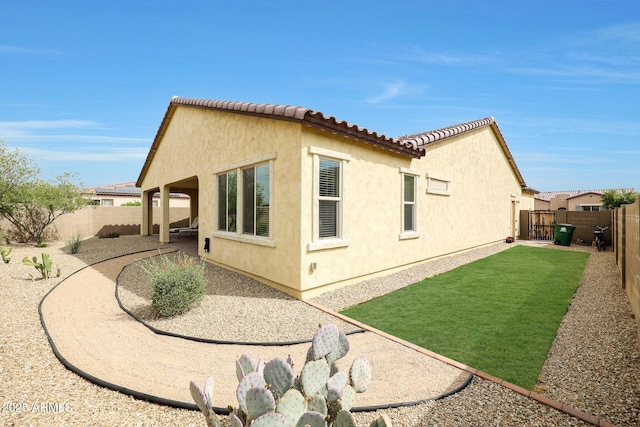 view of side of property featuring a patio, a fenced backyard, stucco siding, and a tile roof