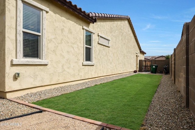 view of side of property with a yard, a fenced backyard, and stucco siding