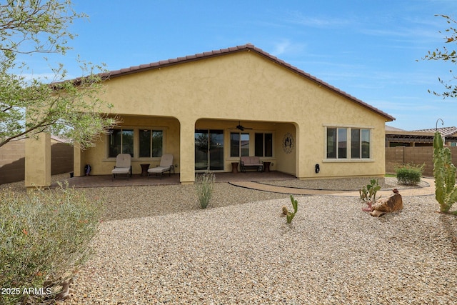 rear view of house with fence, a patio area, stucco siding, and a ceiling fan
