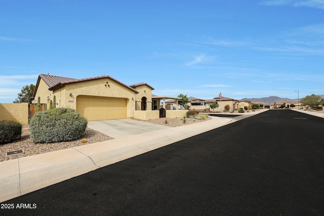 view of front of home featuring stucco siding, driveway, an attached garage, a tile roof, and fence