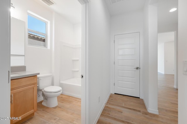 bathroom featuring wood finished floors, vanity, baseboards, toilet, and visible vents