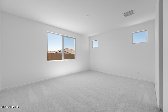 spare room featuring baseboards, carpet flooring, visible vents, and plenty of natural light