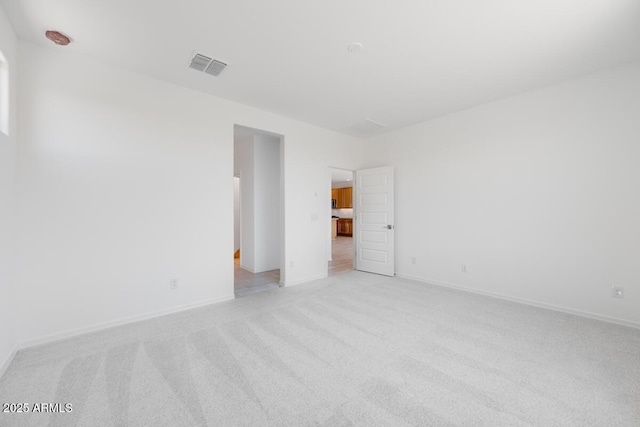 unfurnished room featuring baseboards, visible vents, and light colored carpet