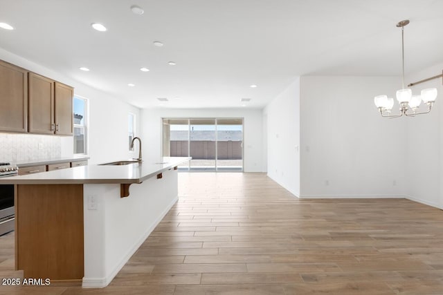 kitchen featuring recessed lighting, light countertops, a sink, light wood-style floors, and open floor plan