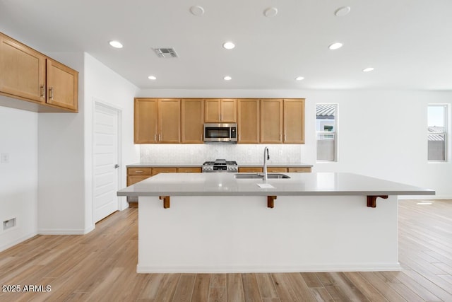 kitchen featuring appliances with stainless steel finishes, a sink, visible vents, and light wood-style flooring