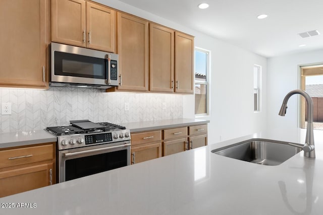 kitchen featuring backsplash, stainless steel appliances, light countertops, and a sink