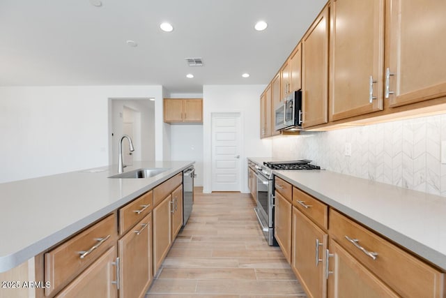 kitchen with a sink, stainless steel appliances, backsplash, visible vents, and recessed lighting