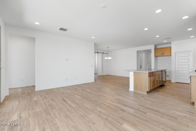 kitchen featuring stainless steel dishwasher, a sink, a barn door, open floor plan, and visible vents