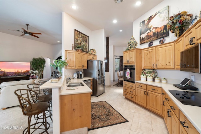 kitchen with appliances with stainless steel finishes, sink, a kitchen bar, light tile patterned floors, and kitchen peninsula