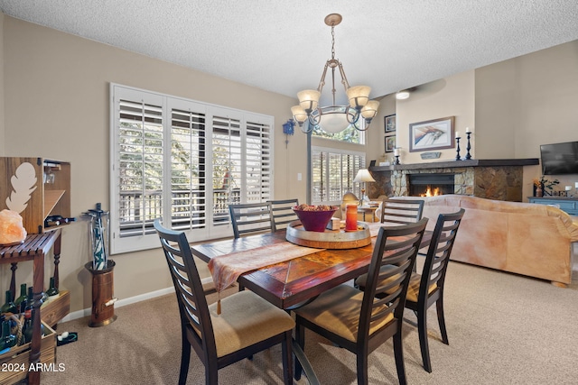 dining room with a stone fireplace, light carpet, a textured ceiling, and a chandelier