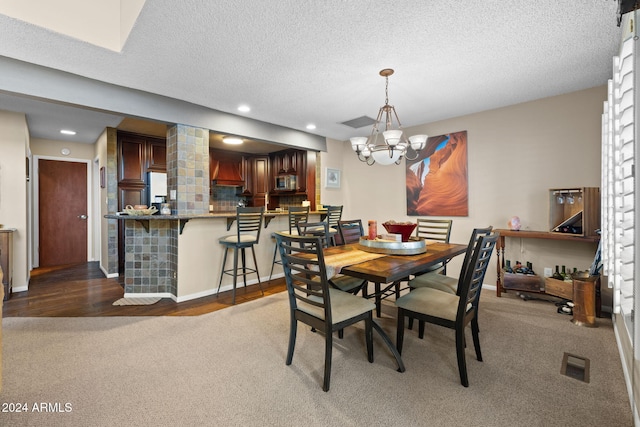 dining space with dark carpet, a notable chandelier, and a textured ceiling