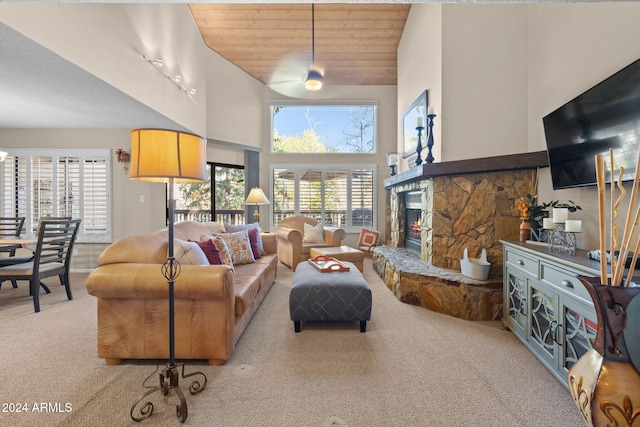 living room featuring light colored carpet, a fireplace, a high ceiling, and wooden ceiling