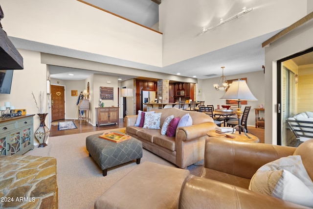 living room with a notable chandelier, a towering ceiling, and light wood-type flooring