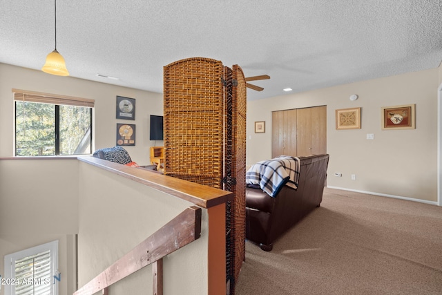 carpeted living room with ceiling fan and a textured ceiling