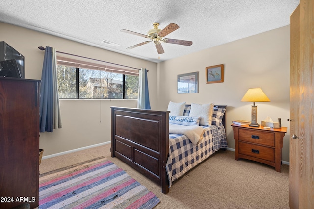 carpeted bedroom with ceiling fan and a textured ceiling