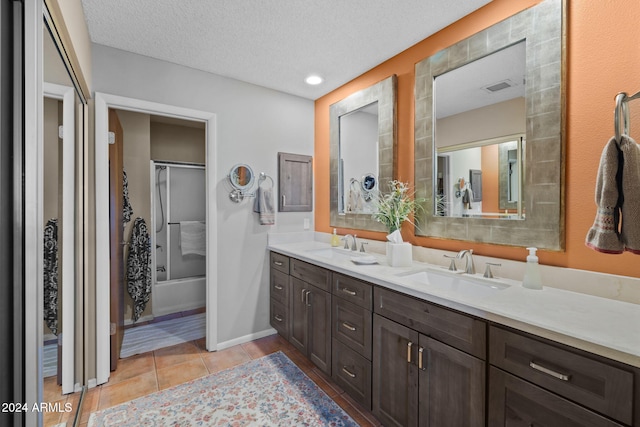 bathroom with tile patterned floors, vanity, shower / bath combination with glass door, and a textured ceiling