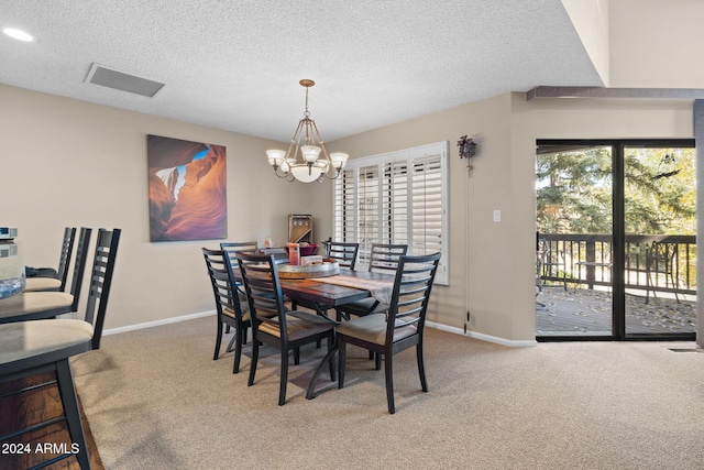 carpeted dining area with a textured ceiling and a chandelier