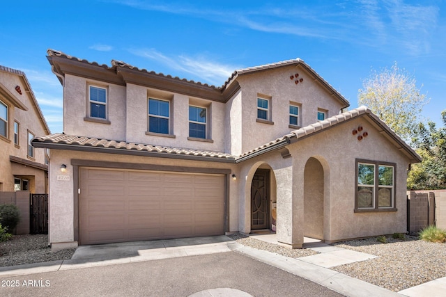 mediterranean / spanish home with an attached garage, fence, and stucco siding