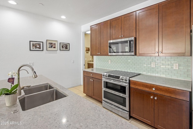 kitchen with a sink, tasteful backsplash, appliances with stainless steel finishes, and light tile patterned floors