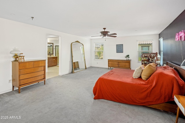 bedroom featuring ceiling fan, baseboards, light carpet, and ensuite bath