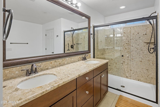 bathroom featuring tile patterned flooring, a shower stall, double vanity, and a sink