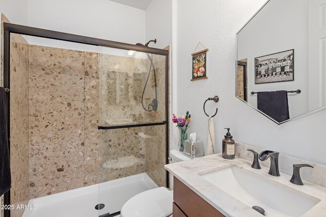 bathroom with a shower stall, toilet, and vanity