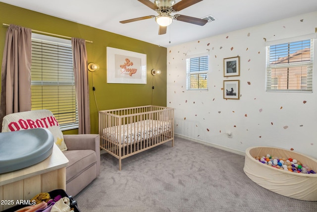 bedroom with visible vents, baseboards, ceiling fan, a crib, and carpet flooring