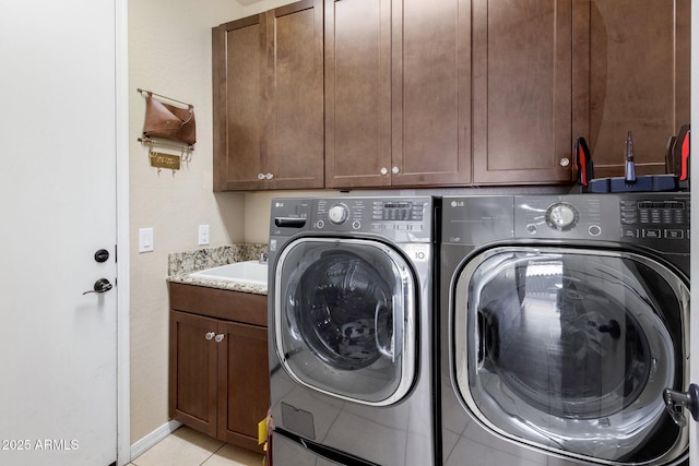 washroom featuring independent washer and dryer, a sink, cabinet space, light tile patterned flooring, and baseboards