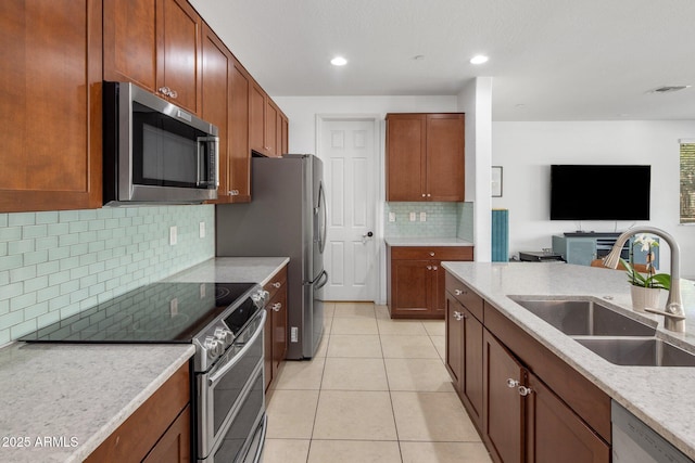 kitchen with visible vents, a sink, open floor plan, appliances with stainless steel finishes, and light tile patterned flooring