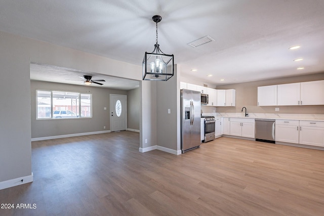 kitchen featuring pendant lighting, white cabinets, sink, light hardwood / wood-style floors, and stainless steel appliances