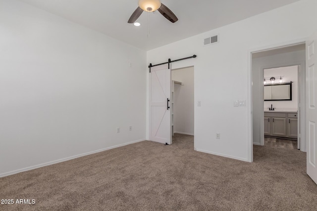 20100 N 78th Pl Unit 2114, Scottsdale, AZ 85255 - unfurnished bedroom with a barn door, carpet floors, a spacious closet, and ceiling fan