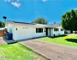 single story home with a front lawn and solar panels