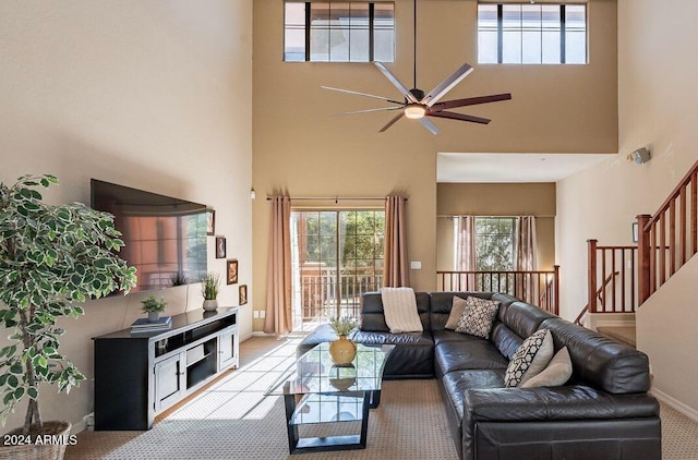 carpeted living room with ceiling fan and a towering ceiling