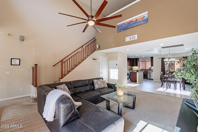 living room with ceiling fan with notable chandelier, light carpet, and a high ceiling