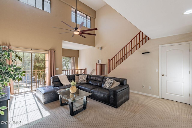 living room with ceiling fan, light carpet, and a high ceiling