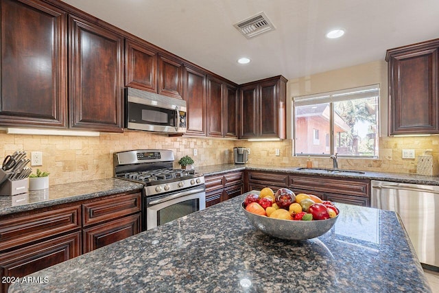 kitchen featuring dark stone countertops, sink, appliances with stainless steel finishes, and tasteful backsplash