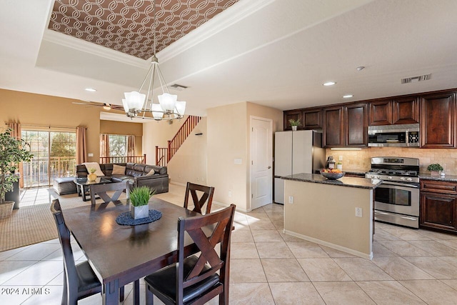 kitchen with dark brown cabinetry, stainless steel appliances, a raised ceiling, dark stone counters, and a kitchen island