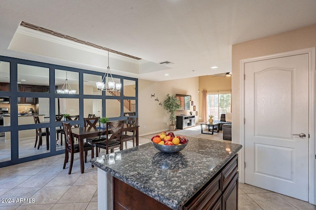 kitchen with light tile patterned floors, ceiling fan with notable chandelier, a tray ceiling, and hanging light fixtures